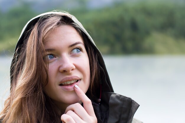 Porträt einer jungen Frau in einer Kapuze bringt ihre Finger ihre Lippen Nahaufnahme