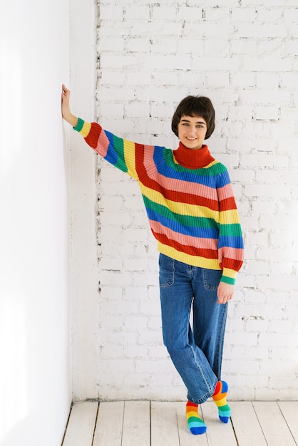 Porträt einer jungen Frau in Jeans und einem Regenbogenpullover hochwertiges Foto