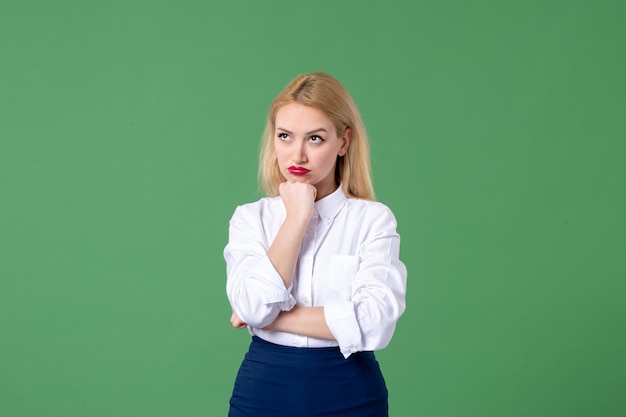 Porträt einer jungen Frau in konservativer Kleidung, die an eine grüne Wand denkt