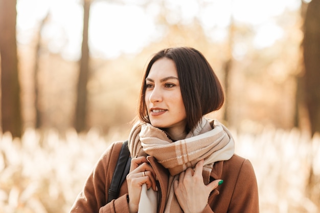 Porträt einer jungen Frau in Mantel und Schal im Herbst im Park