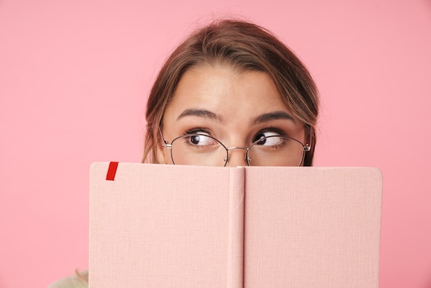 Porträt einer jungen Frau mit Brille, die Tagebuch hält und beiseite schaut