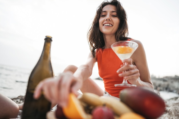 Porträt einer jungen Frau mit Cocktailglas, die an einem Strand kühlt