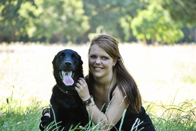 Porträt einer jungen Frau mit einem auf Gras sitzenden Hund