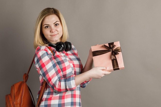 Porträt einer jungen Frau mit einem Geschenk Student im karierten Hemd auf grauem Hintergrund