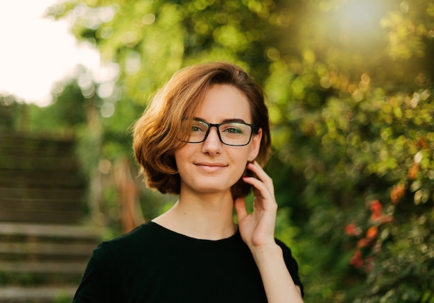 Porträt einer jungen Frau mit einem kurzen Haarschnitt und einer Brille im Freien