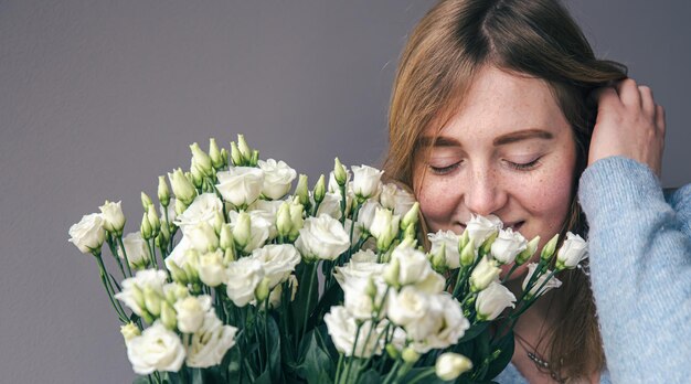 Porträt einer jungen Frau mit einem Strauß Rosen auf grauem Hintergrund