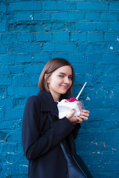 Porträt einer jungen Frau mit Eis an einer blauen Wand