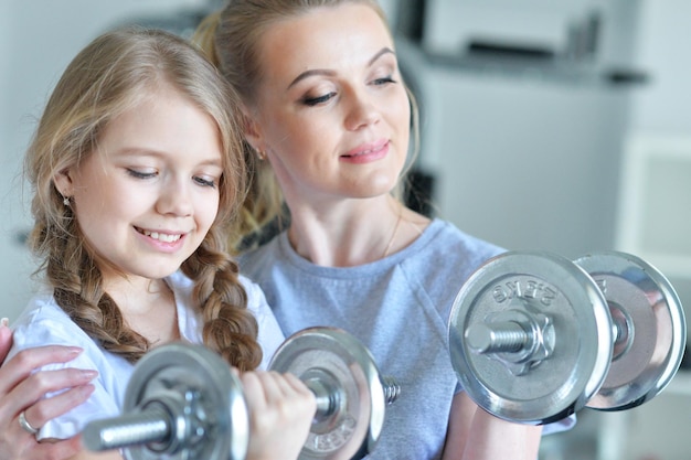 Porträt einer jungen Frau mit ihrer Tochter im Teenageralter in einem Fitnessstudio mit Hanteln