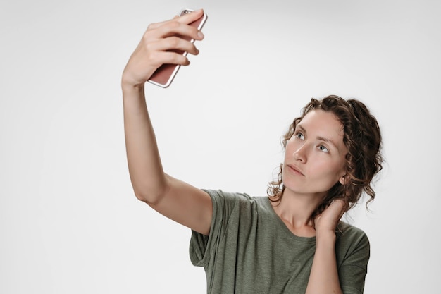 Porträt einer jungen Frau mit lockigem Haar, die einen Videoanruf mit einem Smartphone hat