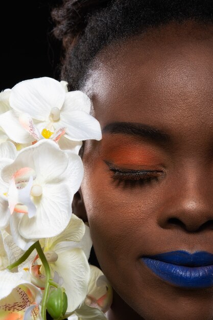 Porträt einer jungen Frau mit orange Make-up und Blume