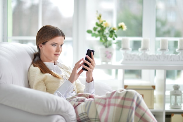 Porträt einer jungen Frau mit Smartphone zu Hause