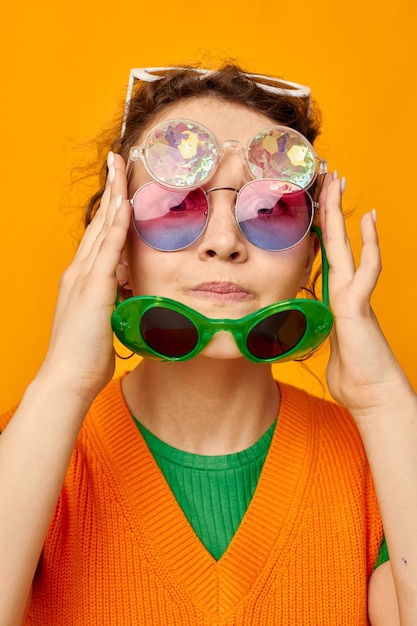 Porträt einer jungen Frau, orangefarbene Sweatshirts, Sonnenbrillen, bunte Gläser, liefern unveränderten Lebensstil