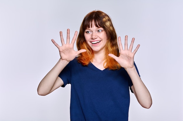 Porträt einer jungen, fröhlichen Frau mit roten Haaren auf hellem Studiohintergrund