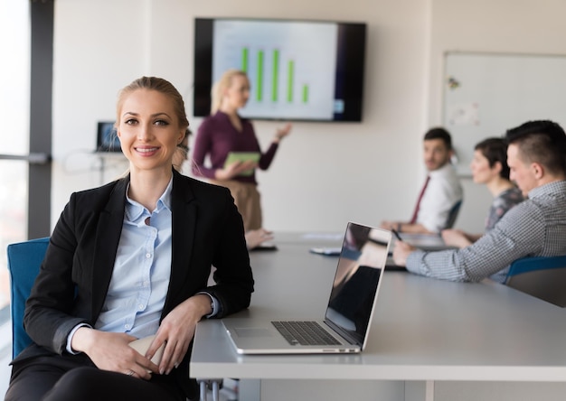 Porträt einer jungen Geschäftsfrau im modernen Startup-Büroinnenraum, Team in der Besprechungsgruppe im Hintergrund