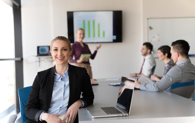 Porträt einer jungen Geschäftsfrau im modernen Startup-Büroinnenraum, Team in der Besprechungsgruppe im Hintergrund