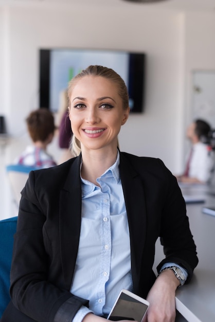 Porträt einer jungen Geschäftsfrau im modernen Startup-Büroinnenraum, Team in der Besprechungsgruppe im Hintergrund