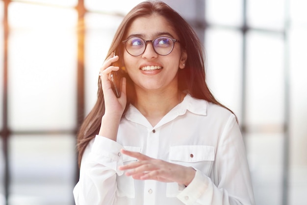 Porträt einer jungen Geschäftsfrau mit Brille und telefonierend