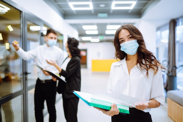 Foto porträt einer jungen geschäftsfrau mit schützender gesichtsmaske auf einem flur eines bürogebäudes