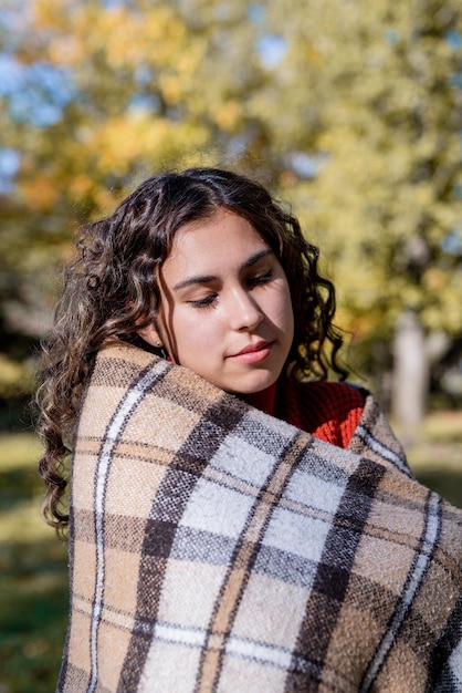 Porträt einer jungen glücklichen Frau in warmem Plaid im Herbstwald