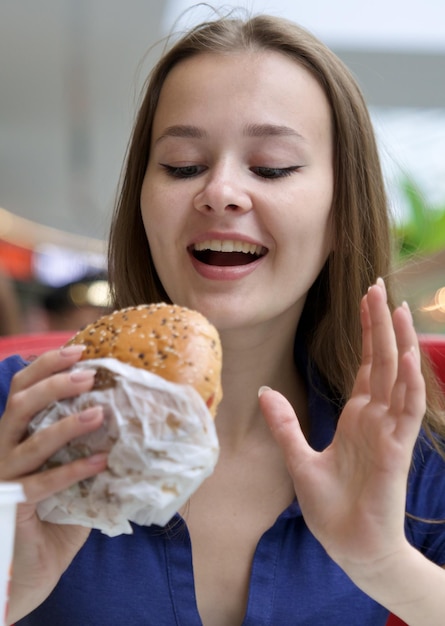 Foto porträt einer jungen glücklichen frau oder eines schönen teenagermädchens, das schnelles junkfood, leckeren burger und