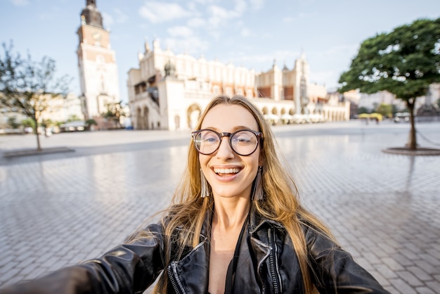 Porträt einer jungen glücklichen Touristin vor der Tuchhalle auf dem Marktplatz im Morgenlicht in Krakau, Polen