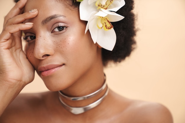 Porträt einer jungen halbnackten sommersprossigen Afroamerikanerin mit Blumen im Haar