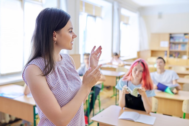 Foto porträt einer jungen highschool-lehrerin im unterricht. sprechende lehrerin im unterricht mit schülern im teenageralter
