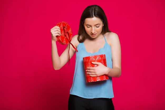 Porträt einer jungen, hübschen, süßen, glamourösen Mädchendame, die eine Geschenkbox mit grauem Oberteil trägt