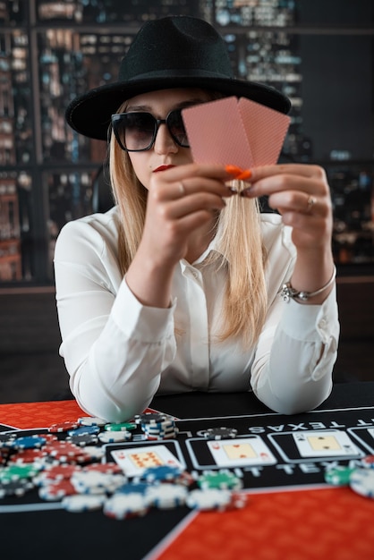 Porträt einer jungen kaukasischen Frau mit Karten und Chips, die im Casino Poker spielt