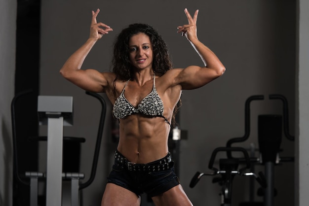 Porträt einer jungen körperlich fitten Frau, die ihren gut trainierten Körper zeigt. Muskulöser athletischer Bodybuilder Fitness Model posiert nach Übungen