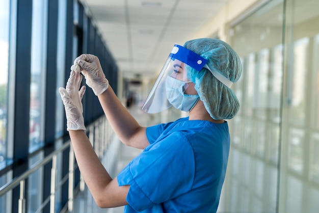 Porträt einer jungen Krankenschwester in blauer Uniform und Schutzschild zum Schutz vor einem neuen gefährlichen Virus covid19