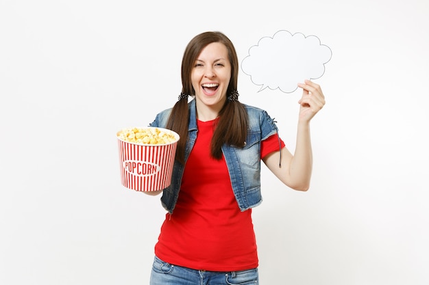 Porträt einer jungen lachenden Frau in Freizeitkleidung, die einen Filmfilm anschaut und eine Wolke mit Platz für Text, Kopienraum und Eimer Popcorn auf weißem Hintergrund hält. Emotionen im Kinokonzept.