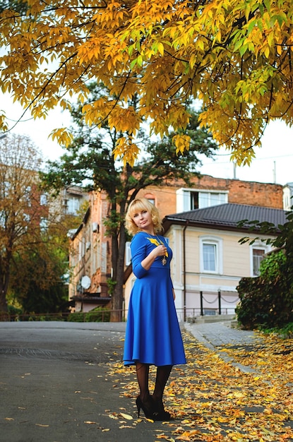 Porträt einer jungen lässigen blonden Frau mit blauen Augen, die in den Straßen der Herbststadt spaziert. Herbstsaison.