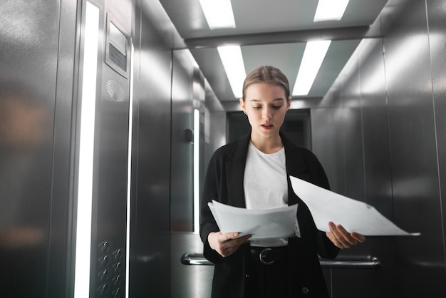 Porträt einer jungen Mitarbeiterin, die die im Aufzug stehenden Dokumente liest