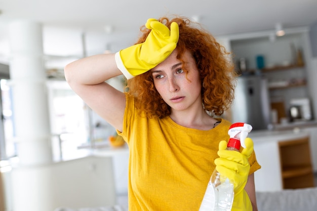 Porträt einer jungen, müden Frau mit Gummihandschuhen, die sich nach der Reinigung einer Wohnung ausruhen Hauswirtschaftskonzept