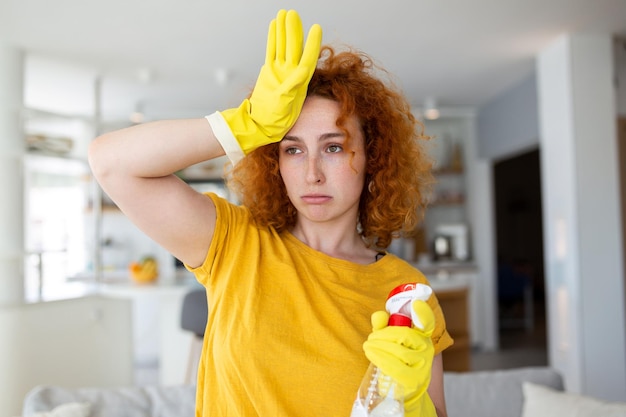 Porträt einer jungen müden Frau mit Gummihandschuhen, die sich nach der Reinigung einer Wohnung ausruht