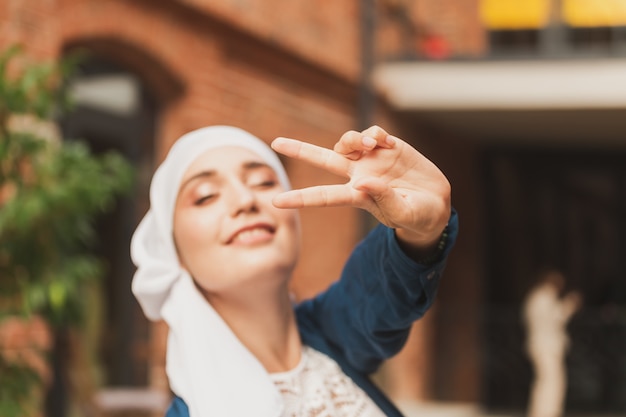 Porträt einer jungen muslimischen Frau mit Hijab-Kopftuch in der Stadt, während sie das Gesicht der Kamera in Nahaufnahme betrachtet