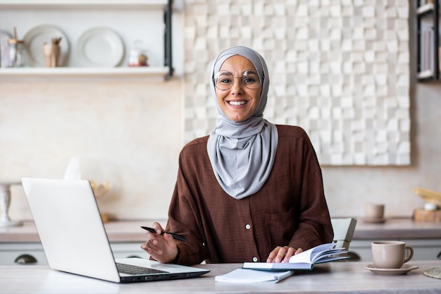 Porträt einer jungen muslimischen Psychologin mit Hijab, die zu Hause vor einem sitzt