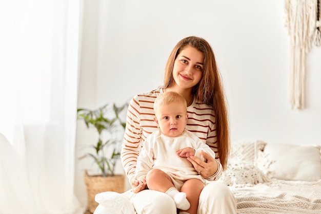 Porträt einer jungen Mutter mit einem Baby im Arm Mutterschaft