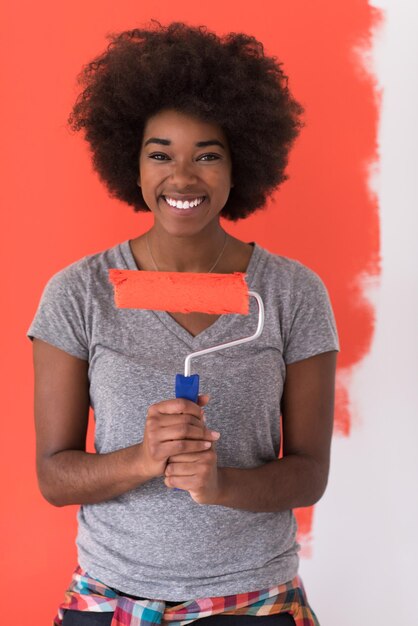 Porträt einer jungen schönen afroamerikanischen Frau, die in ihrer neuen Wohnung eine Wand malt