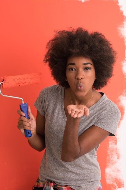 Porträt einer jungen schönen afroamerikanischen Frau, die in ihrer neuen Wohnung eine Wand malt