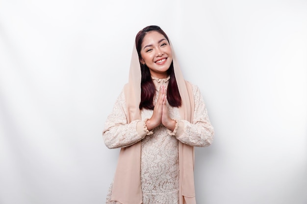 Porträt einer jungen schönen asiatischen muslimischen Frau, die ein Kopftuch trägt und Eid Mubarak-Gruß gestikuliert