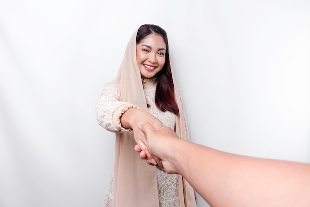 Porträt einer jungen schönen asiatischen muslimischen Frau, die ein Kopftuch trägt und Eid Mubarak-Gruß gestikuliert