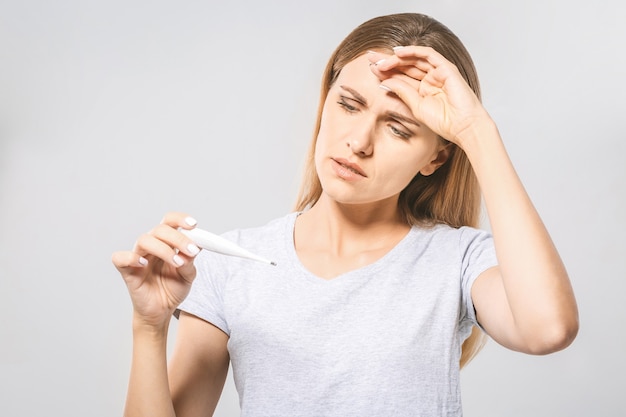 Porträt einer jungen schönen Frau, die ihre Temperatur prüft