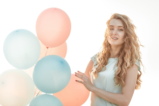 Porträt einer jungen schönen Frau mit fliegenden bunten Luftballons gegen den Himmel