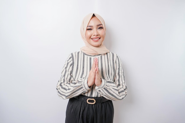 Porträt einer jungen schönen muslimischen Frau, die einen Hijab trägt und Eid Mubarak-Gruß gestikuliert