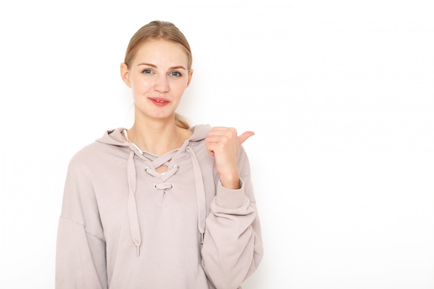 Porträt einer jungen traurigen lächelnden europäischen frau mit blonden haaren. ihre augen drücken traurigkeit aus. der daumen ihrer gebogenen linken hand zeigt nach links.