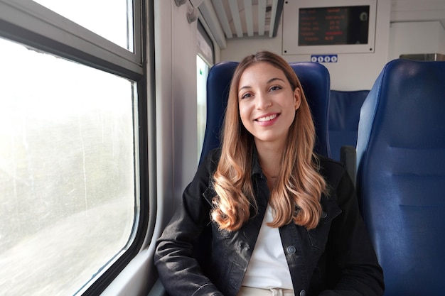 Porträt einer jungen zufriedenen Frau, die mit öffentlichen Verkehrsmitteln unterwegs ist und entspannt gedankenlos sitzt Blick in die Kamera