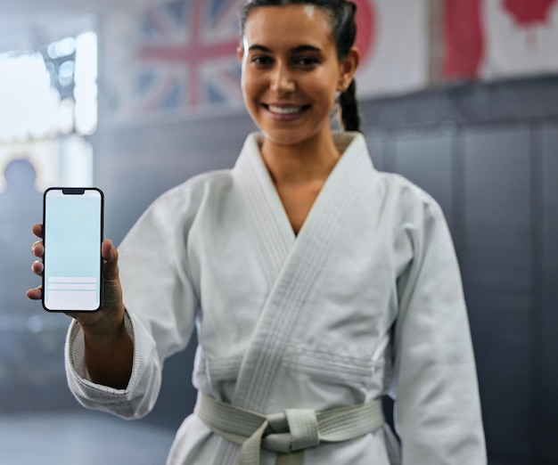 Porträt einer Karate-Studentin, die Tech mit Social Media hält und im Unterricht aktiv und fit aussieht