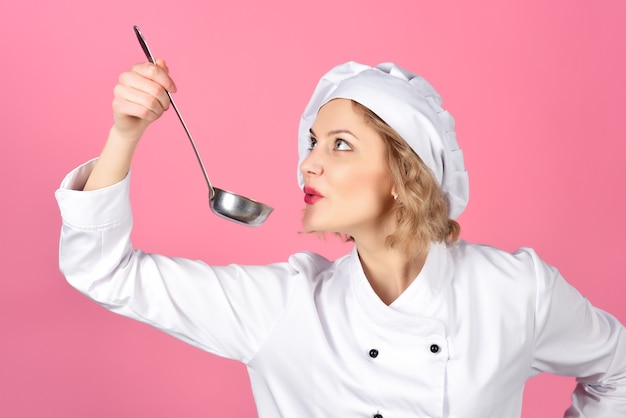 Porträt einer Köchin, die einen Löffel mit heißem Essen hält, eine Frau, die Suppe mit Gemüse in der Küche kocht